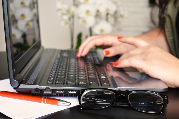 Woman with Red Fingernails Typing on a Laptop